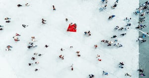 Luftaufnahme eines Platzes mit verteilten Personen und rotem Akzent
