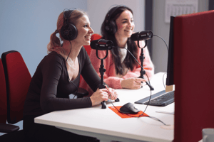 Zwei Personen sprechen in Mikrofone bei einer Podcast-Produktion