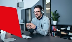 Mitarbeiter mit Headset sitzt vor dem Computer und führt ein Gespräch im modernen Büro.