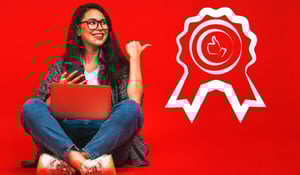 Frau mit Laptop und Smartphone sitzt vor rotem Hintergrund und zeigt auf ein Qualitätssiegel.