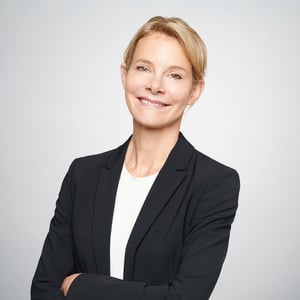 A professional portrait of Anke Barnaschewski, smiling friendly at the camera in front of a gray background