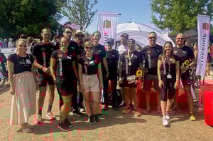 DATAGROUP Kolleginnen und Kollegen beim Triathlon Nürnberg posieren gemeinsam für ein Gruppenfoto mit Blumen und Medaillen.