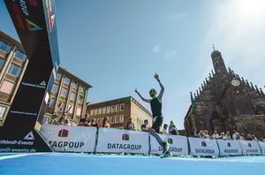 Athlet beim Zieleinlauf am Nürnberger Hauptmarkt beim DATAGROUP Triathlon, im Hintergrund die Frauenkirche.