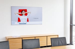 Büroraum bei DATAGROUP Ulm mit Wandbild einer entspannt zurückgelehnten Frau und dem Schriftzug „IT’s that simple“.