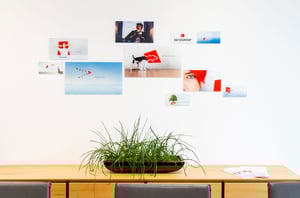 Wandgestaltung im DATAGROUP Büro Ulm mit verschiedenen Unternehmensmotiven und Slogans, darunter Bilder von Personen, Symbolen und Markenfarbe Rot.