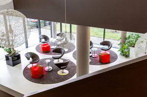 Offene Lounge im DATAGROUP Büro Ulm mit runden Teppichen, Sesseln und roten Sitzwürfeln als Farbakzent.
