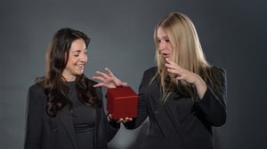 Zwei Frauen beim Podcast-Shooting „Unboxing IT“, halten und präsentieren einen roten Würfel