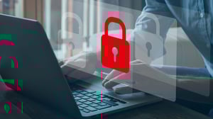 Person tippt auf einem Laptop, darüber eingeblendet ein rotes Schloss-Symbol – Symbol für IT-Sicherheit und den Schutz sensibler Daten im Rahmen der Cyber Security Risikoanalyse.