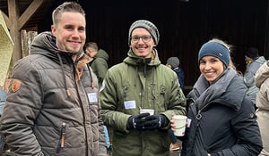 Drei Kolleg:innen von DATAGROUP genießen heiße Getränke auf dem Weihnachtsmarkt in Frankfurt – geselliges Beisammensein in der Kälte.