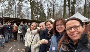 Mitarbeiterinnen von DATAGROUP lächeln beim Selfie auf dem Weihnachtsmarkt in Frankfurt – gemeinsamer Besuch mit winterlicher Stimmung und Lichterketten.