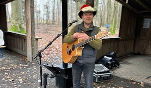 Musiker mit Weihnachtsmütze spielt Gitarre auf dem DATAGROUP Weihnachtsmarkt in Frankfurt – sorgt für festliche Stimmung und Unterhaltung.