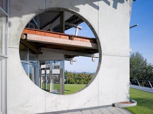 Rundes Fensterdetail an der Fassade des DATAGROUP Hauptsitzes in Pliezhausen mit Blick auf Terrasse und Grünflächen.