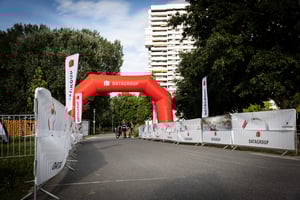 Roter DATAGROUP-Startbogen auf der Laufstrecke des Triathlons Nürnberg 2025 – im Hintergrund Teilnehmende und Zuschauer.