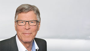 Portraitfoto von Michael Maibaum vor grauem Hintergrund