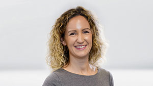 Porträtfoto von Sabrina Enke (Vertrieb) — lächelnd, vor hellgrauem Hintergrund.